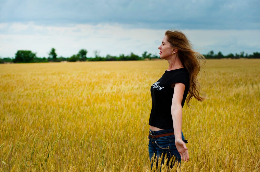 Side view of woman standing with arms stretched out at sides in wheat field. Blog graphic for blog post for awomansoutlook.com
