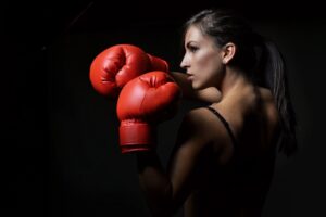 Young woman with boxing gloves. Fight. Blog graphic for blog post 3 ways to help survive an indoor shooter post for awomansoutlook.com. 