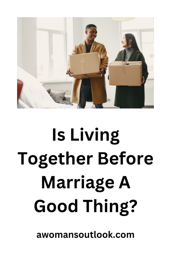 A man and woman standing in an unfurnished apartment with boxes smiling at each other. Blog graphic for blog piece Is Living Together Before Marriage A Good Thing?. awomansoutlook.com