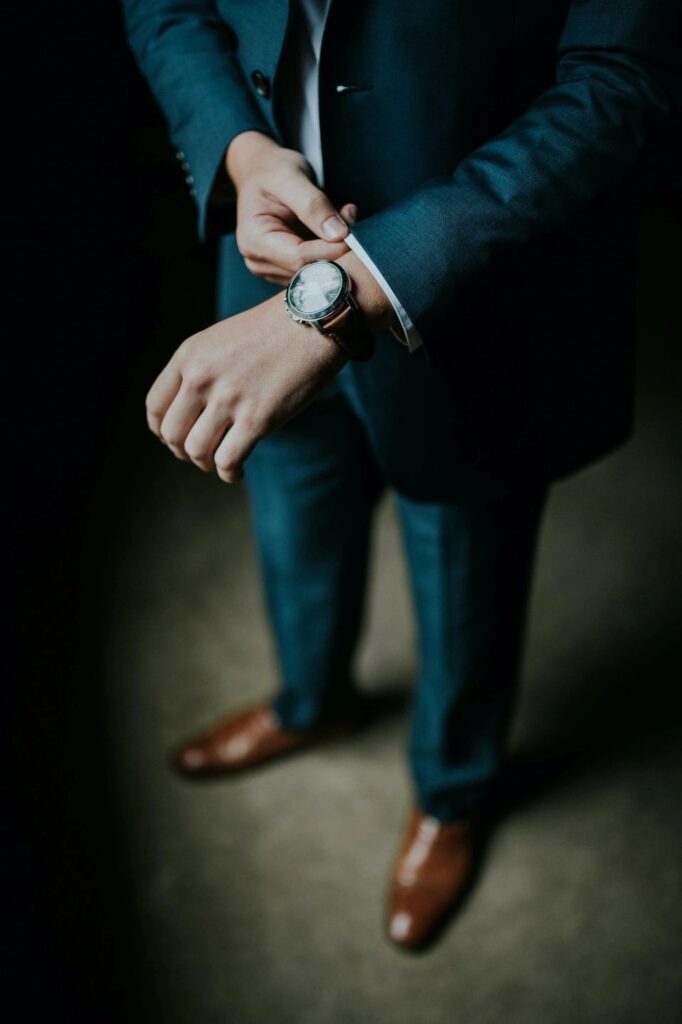 Elbow down view of man in dark suit. Watch on left wrist. Adjusting sleeve of left arm. Blog graphic for blog post mastering workplace attire a guide to dressing professionally for awomansoutlook.com.Image from Pixabay.