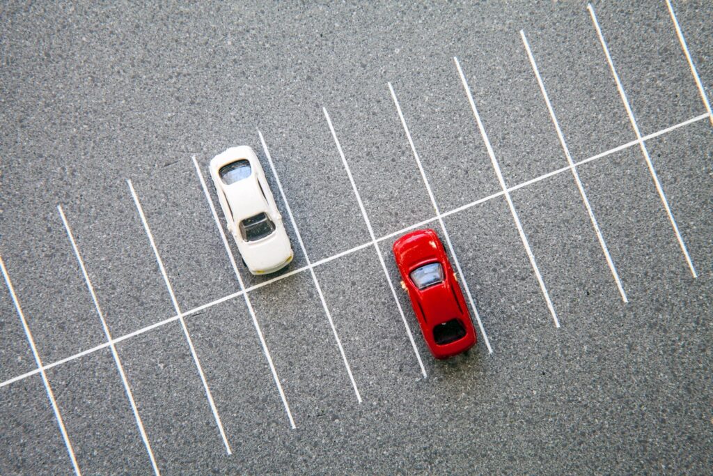 Aerial shot of parking lot with one red car and one white car.  Blog graphic for blog post for awomansoutlook.com