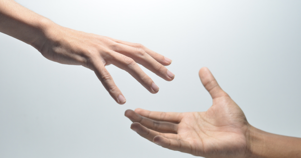 One hand is reaching toward another which is hand up. The background is white toward middle top fading to pale blue throughout the rest of the photo. Blog photo for blog post how a simple act of kindness led to an unexpected friendship at awomansoutlook.com